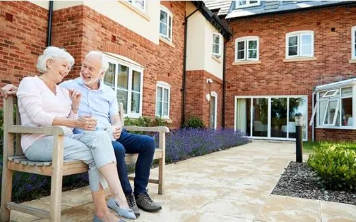 Senior couple sitting on a bench outside a care residence